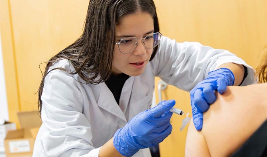 Una enfermera administra la vacuna de la gripe a una paciente.