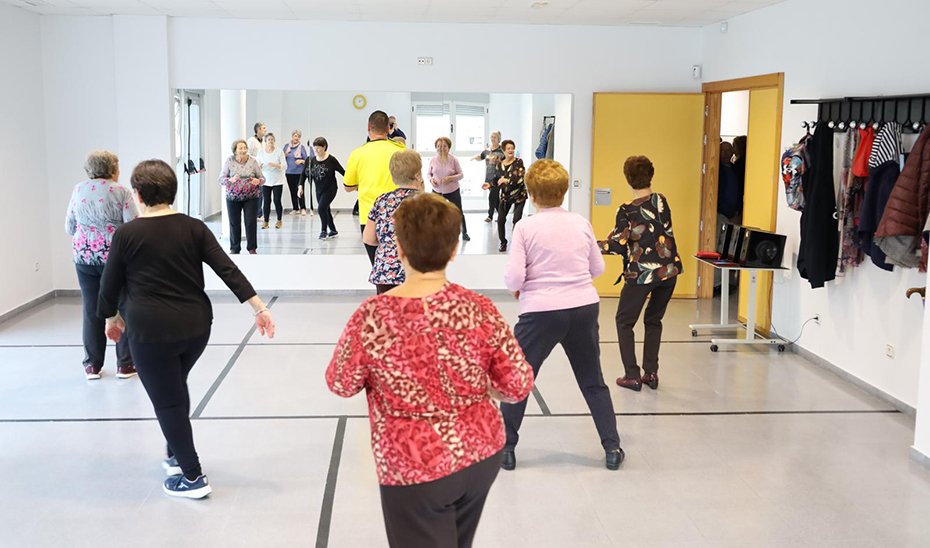 Grupo de personas mayores realiza gimnasia en un centro de participación activa.