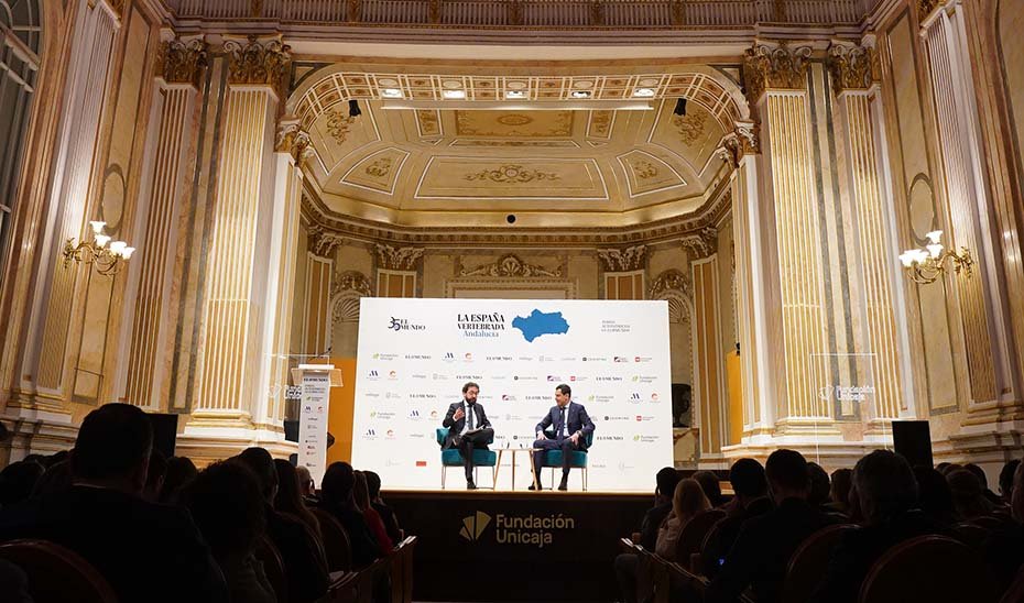 General view of the Fundación Unicaja María Cristina Hall where the event took place, with the Andalusian President and the El Mundo newspaper director on stage during the colloquium.