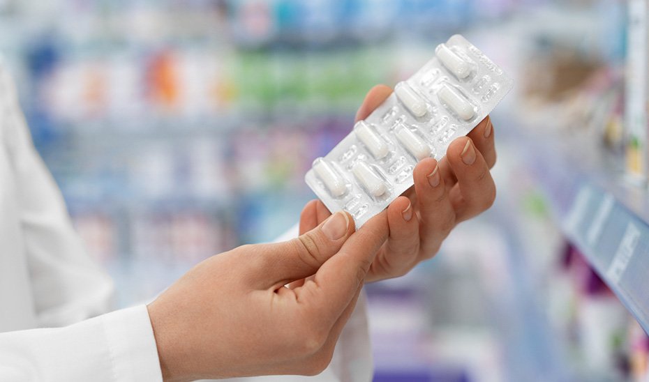 Una mujer muestra una tableta de pastillas.