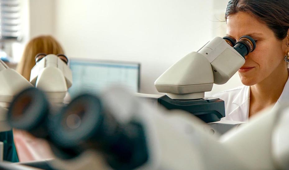 Una investigadora observa una muestra a través del microscopio.