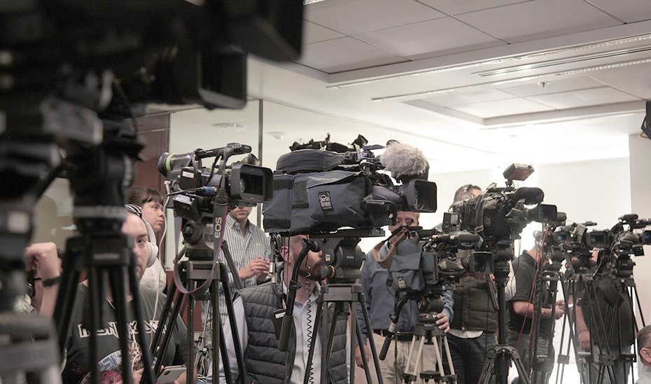Cámaras de televisión apostadas para cubrir un acto informativo.